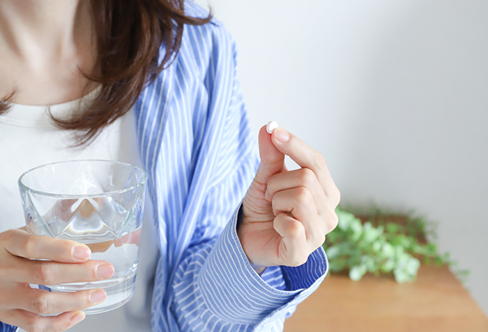 錠剤の薬を飲む女性